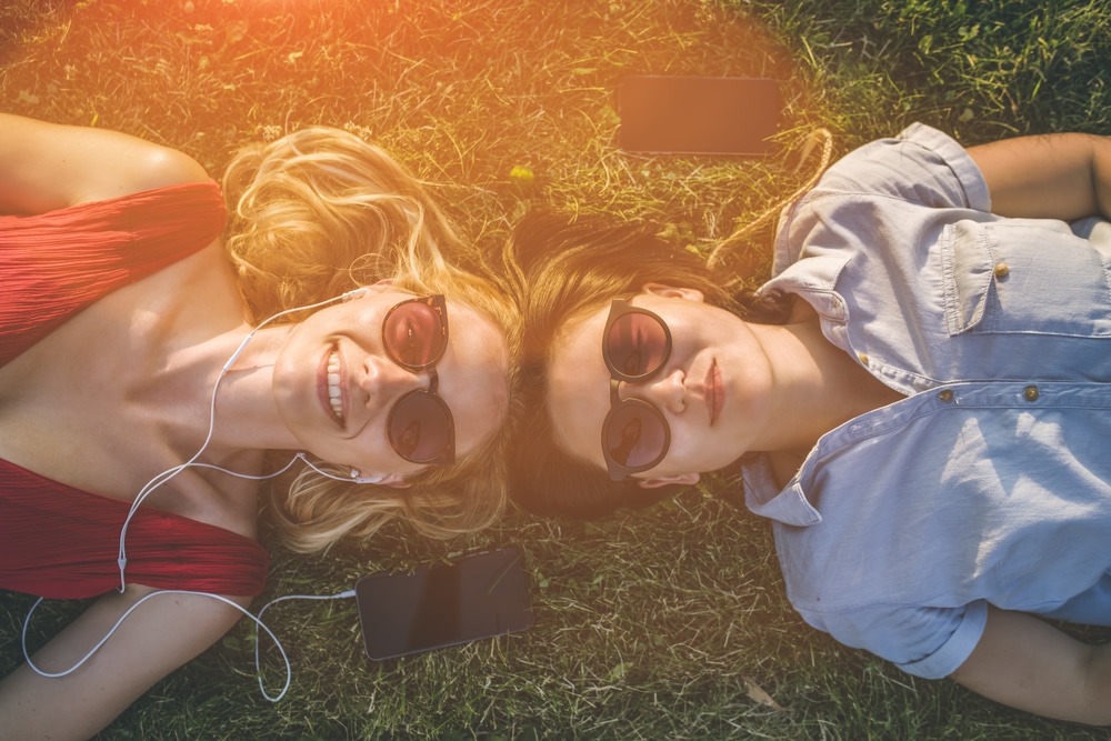 Women laying on the grass wearing sunglasses