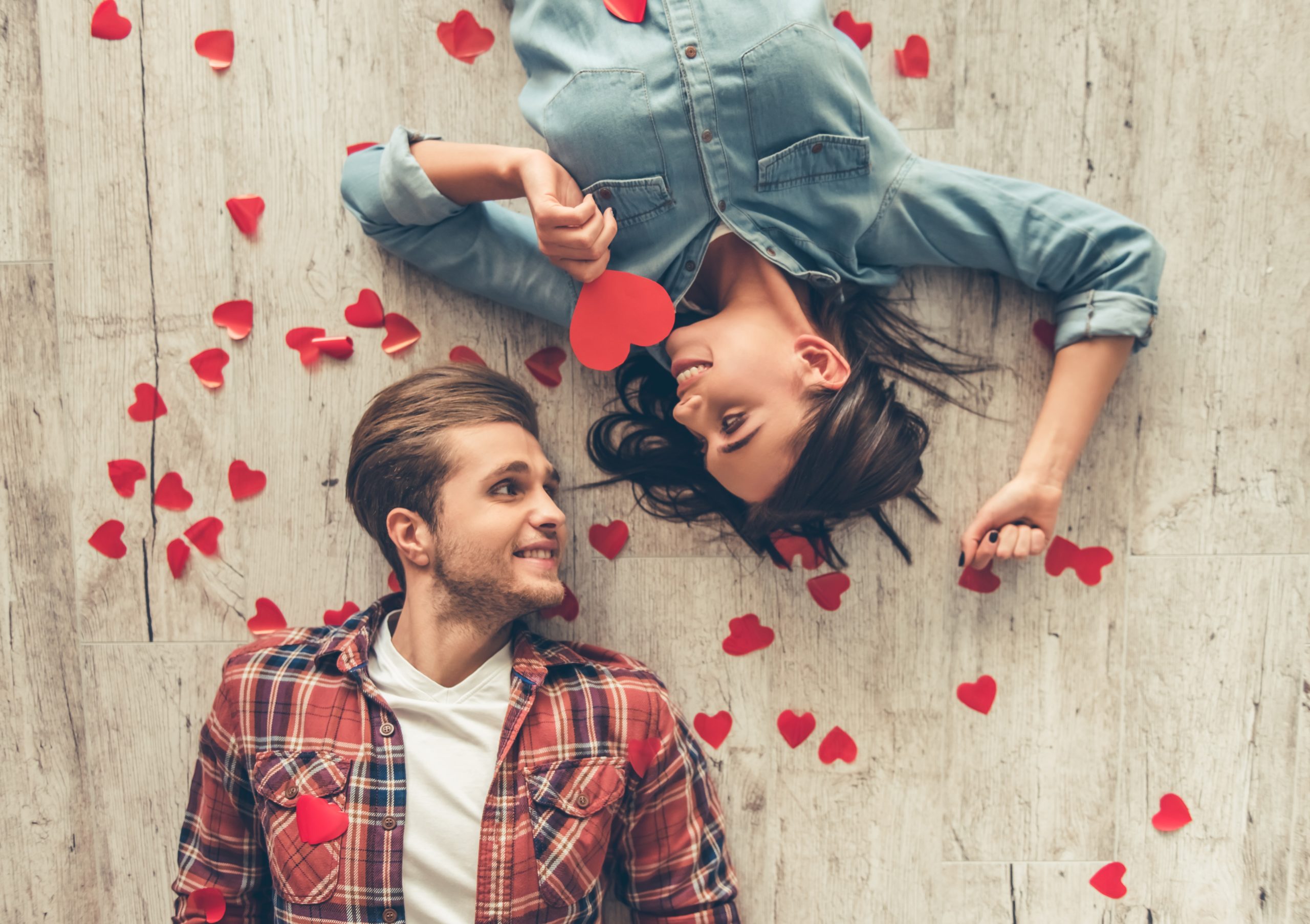 Couple lying on the floor surrounded by hearts