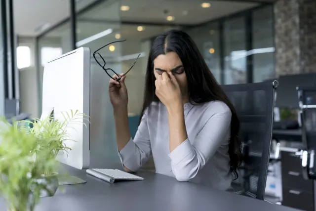 Woman holding her glasses and rubbing her eyes