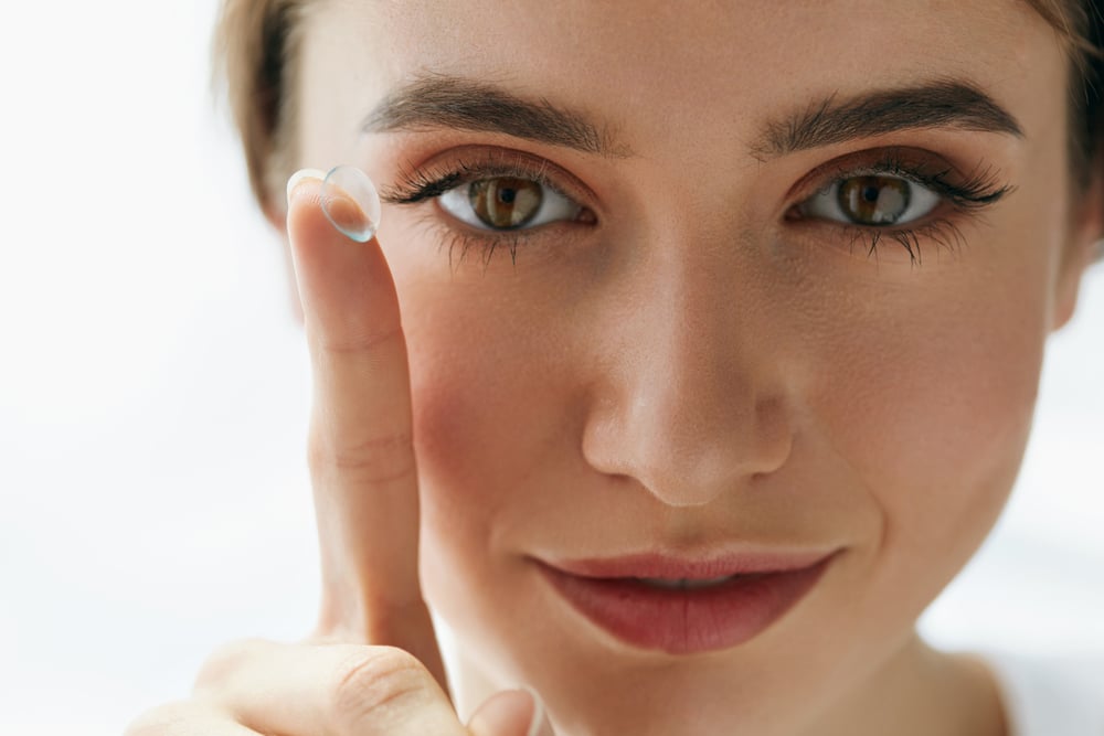 Woman holding a contact lens on the end of her finger