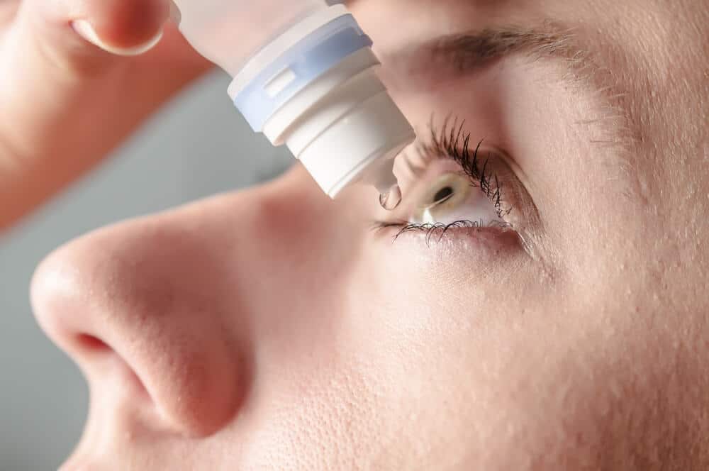 Woman using eye drops for hay fever