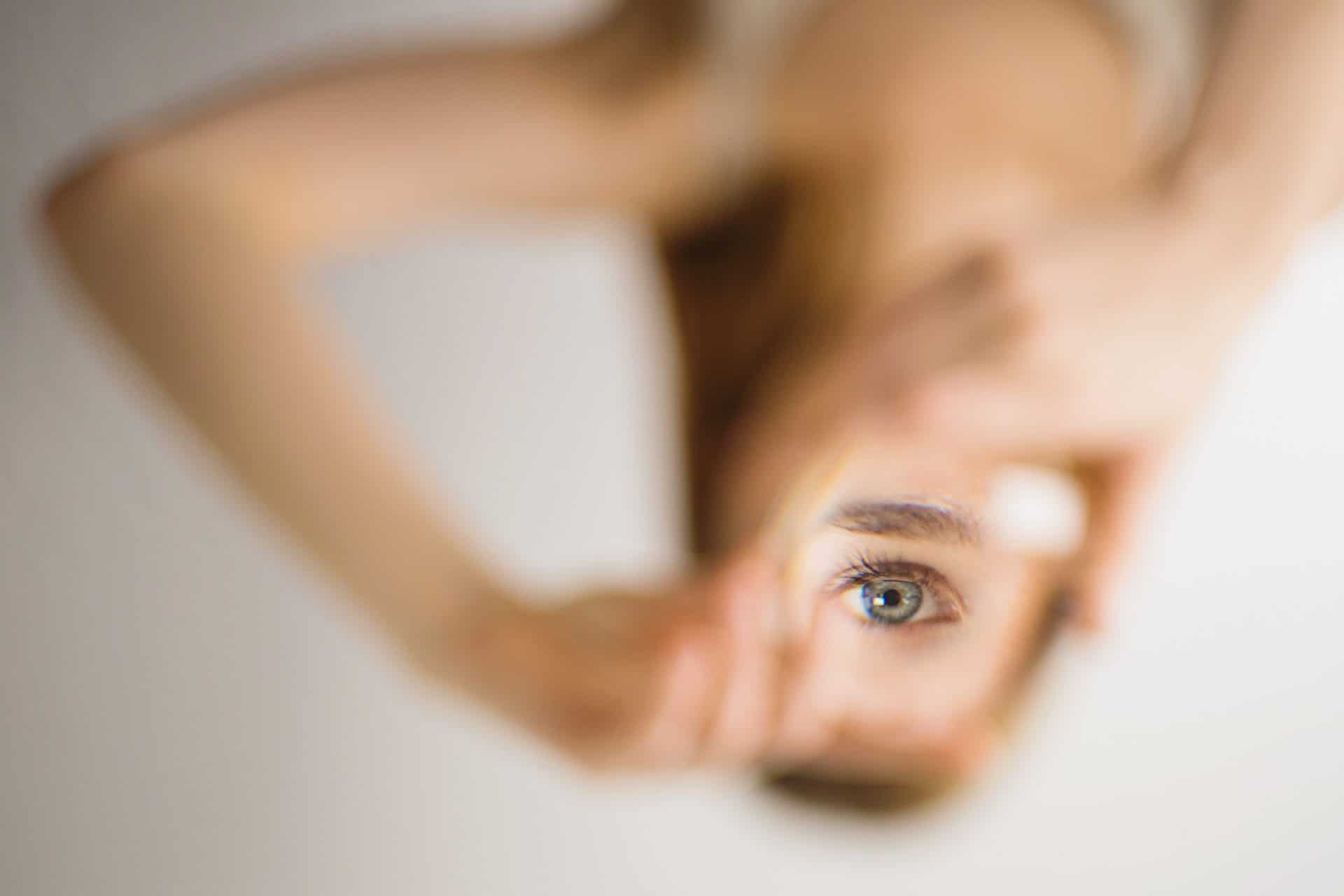 Woman holding a mirror showing her eye