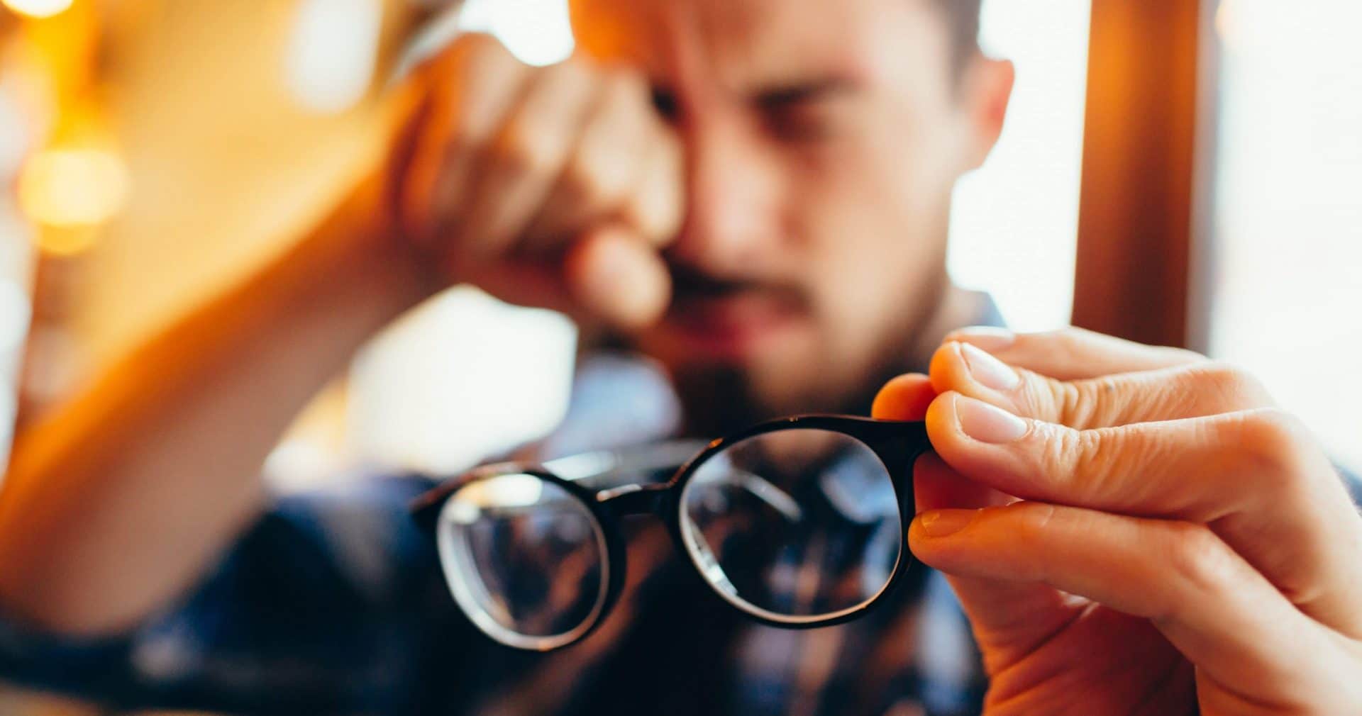 Man holding his glasses and rubbing his eyes